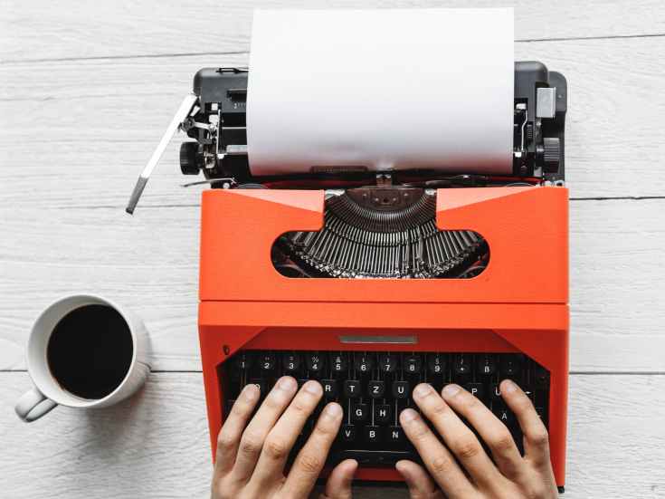 flat lay photo of hands typing on a typewriter